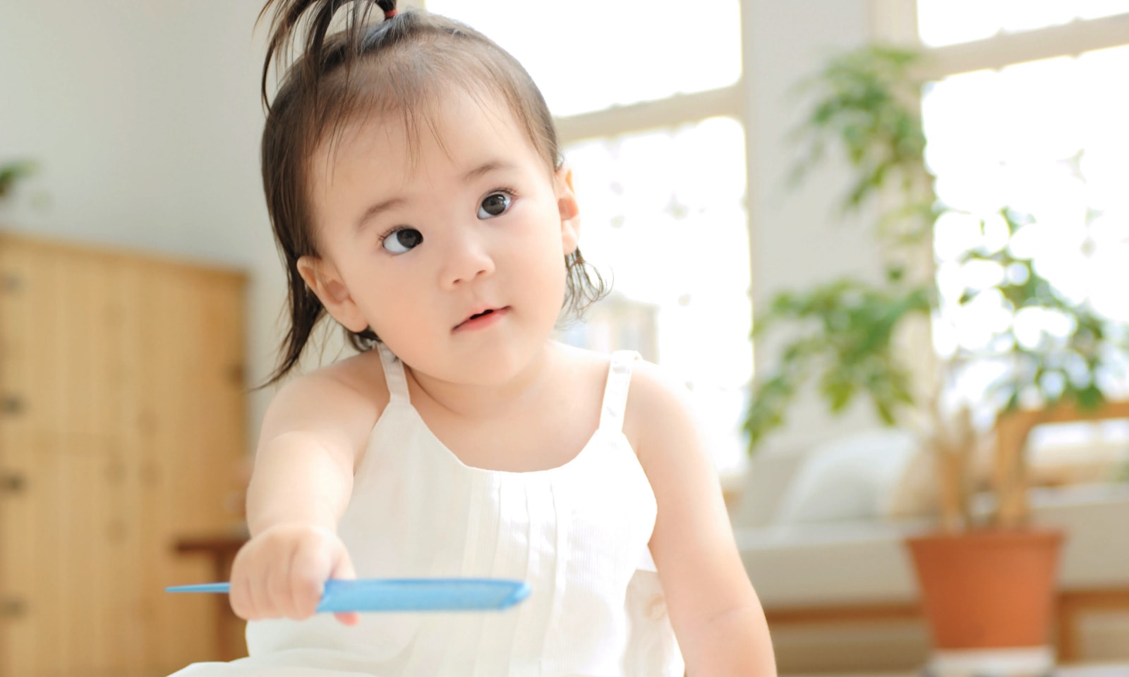 A girl around 1 year old with her hair tied at the top of her head